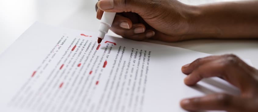 Persona con marcador corrigiendo un examen 
